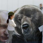 Banner with Russian President Vladimir Putin (left) next to a bear (right) and tow young girls posing next to the bear. Photo: EPA/Anatoly Maltsev.