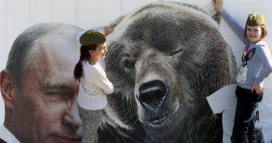 Banner with Russian President Vladimir Putin (left) next to a bear (right) and tow young girls posing next to the bear. Photo: EPA/Anatoly Maltsev.