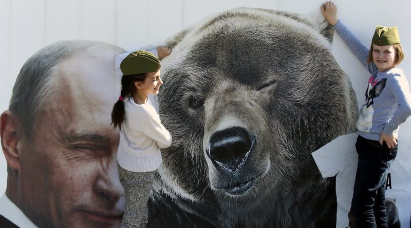 Banner with Russian President Vladimir Putin (left) next to a bear (right) and tow young girls posing next to the bear. Photo: EPA/Anatoly Maltsev.