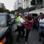 A supporter of Venezuelan President Nicolas Maduro attempts to kick a car which is part of a convoy transporting opposition leader Juan Guaido in Caracas