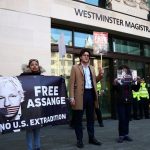 People hold banners in front of Westminster Magistrates Court after WikiLeaks founder Julian Assange was arrested in London