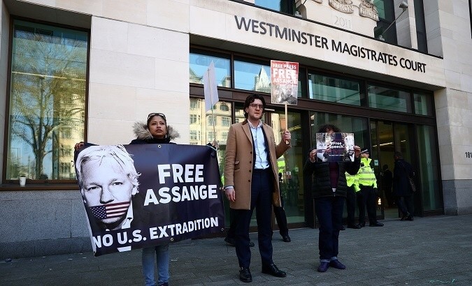 People hold banners in front of Westminster Magistrates Court after WikiLeaks founder Julian Assange was arrested in London