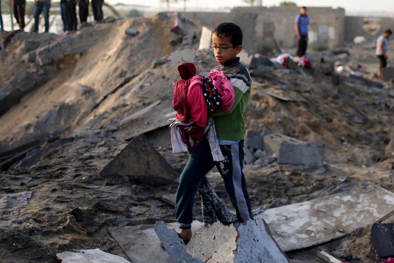 a_palestinian_boy_carries_belongings_retrieved_from_a_house_destroyed_in_an_israeli_air_strike_in_the_southern_gaza_strip_november_13x_2019_