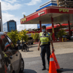 Police officer controlling the access of cars to a PDVSA gas station in Caracas in June, 2020. File photo.