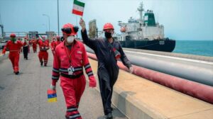 Featured image: A Venezuelan worker waves an Iranian flag celebrating the arrival of the Iranian oil tanker Fortune at a Venezuelan refinery, May 25, 2020 (Photo: AFP).