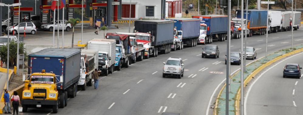 Featured image: Long lines of trucks waiting to load their tanks with fuel and adding to the long lines of cars that are still visible all over Venezuela due to the scarcity created since 2020 as a direct result of US blockade.