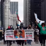 Protesters holding signs navigate along Chicago's South Michigan Avenue during a peaceful protest, on April 14, 2021, ahead of the video release of the fatal police shooting of 13-year-old Adam Toledo.Shafkat Anowar / AP
