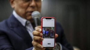 Congressman Pedro Carreño shows a photo of Gilber Caro, a Popular Will politician, posing with criminal gangs. (Photo: National Assembly)