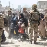 Two Afghan women walking near Kabul's airport surrounded by US soldiers. Photo: Telesur / Getty Images.