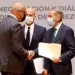 Jorge Rodriguez, head of the Venezuelan government delegation shaking hands with Gerardo Blyde, head of the extreme right opposition delegation while being watch by the head of the Norwegian mediation delegation Dag Nylander. Photo courtesy of Twitter / @AissateleSUR .