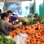 Una mujer que lleva una máscara protectora escoge verduras en un mercado popular durante la cuarentena nacional en respuesta a la propagación de la enfermedad por coronavirus (COVID-19), en Caracas.