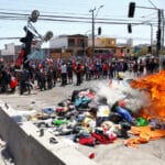 Chileans burning the few belongings of Venezuelan migrants and launching a baby stroller to the fire. Photo courtesy of Twitter.