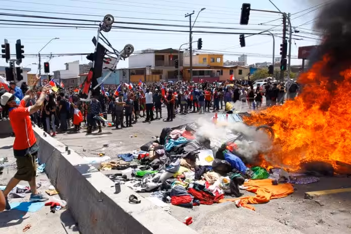 Chileans burning the few belongings of Venezuelan migrants and launching a baby stroller to the fire. Photo courtesy of Twitter.