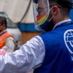 IOM officer in a street wearing a vest and with COVID-19 protective gear. Referential photo.