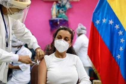 Venezuelan woman being inoculated with an anti COVID-19 vaccine, next to a Venezuelan flag. File photo.