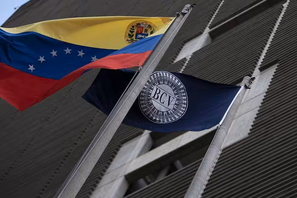 A Venezuelan and a Central Bank of Venezuela (BCV) flag in front ot the BCV headquarters in Caracas, Venezuela. File photo.