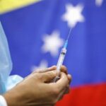 healthcare worker holding a syringe with a Venezuelan flack in the background. File photo.