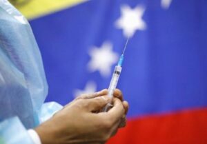 healthcare worker holding a syringe with a Venezuelan flack in the background. File photo.