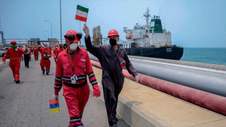 Workers carrying Iranian and Venezuelan flags celebrate the arrival of Iranian tanker Fortune at a Venezuelan refinery.