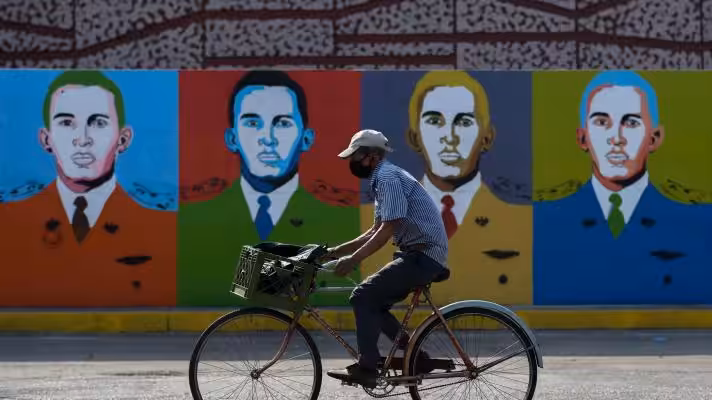 A man rides a bicycle in front of Hugo Chávez graffiti in Barinas on January 7, 2022