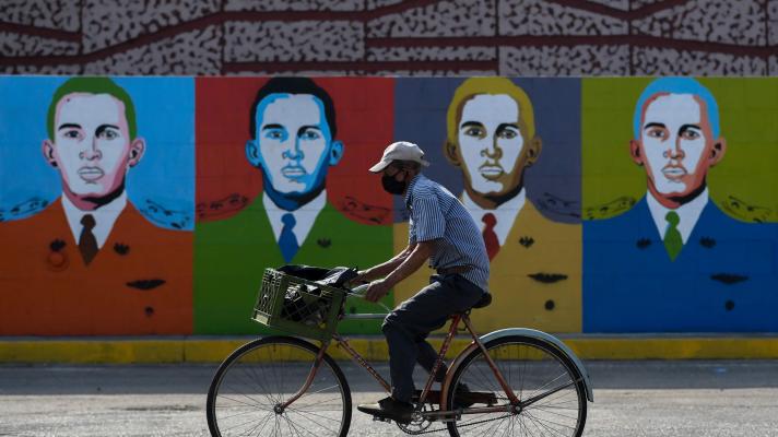 A man rides a bicycle in front of Hugo Chávez graffiti in Barinas on January 7, 2022