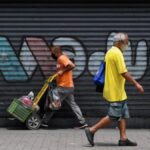 Featured image: People walk down a street in Caracas, Venezuela, with graffiti reading "Maduro" in the background. Photo: AFP