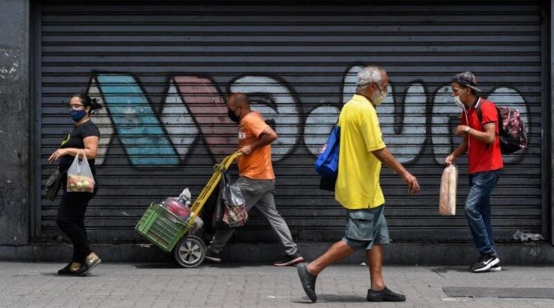 Featured image: People walk down a street in Caracas, Venezuela, with graffiti reading "Maduro" in the background. Photo: AFP