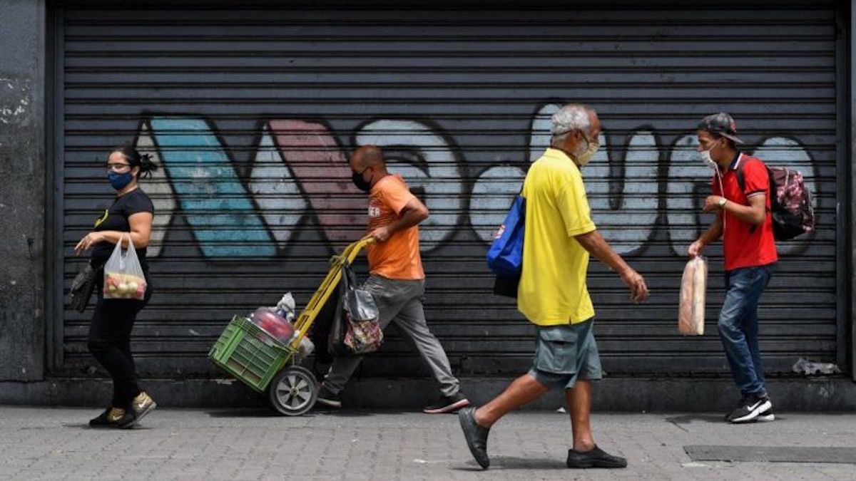 Featured image: People walk down a street in Caracas, Venezuela, with graffiti reading "Maduro" in the background. Photo: AFP