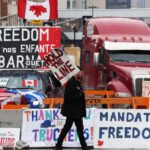 A protester walks in front of parked trucks in Ottawa, Canada. Photo: Dave Chan/AFP