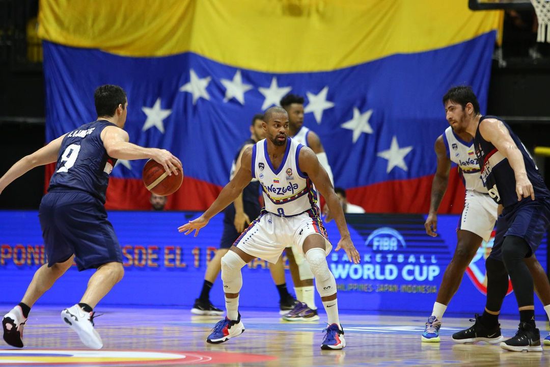 Venezuelan player Gregory Vargas facing two Paraguayan players with the Venezuelan flag in the background. Photo: FVB.