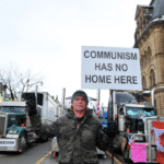 Truckers Convoy’s supporter holding a banner that reads “Communism has no home here.” Photo: Anadolu.