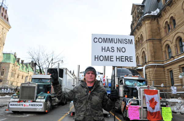 Truckers Convoy’s supporter holding a banner that reads “Communism has no home here.” Photo: Anadolu.