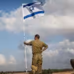 Israeli soldiers at the "buffer zone"—Gaza-Israel border—flying an Israeli flag. Photo: Andrew Burton/Getty Images