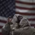 US military personnel dressing with bio hazzard gear and the US flag in the background. Photo: Twitter / @amcchinetchad.