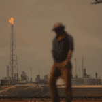 Featured image: A man stands in front of an oil plant. Photo: AP Photo / Natacha Pisarenko. 