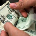 Person holding a batch of US dollar bills. File photo.