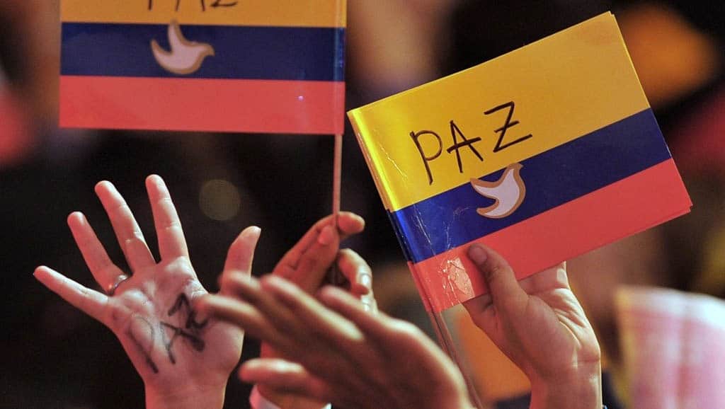 People waving Colombian flags with white doves and peace draw on them. Photo: Warscapes.