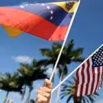 Hand holding small US and Venezuelan flags. File photo.