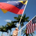 Hand holding small US and Venezuelan flags. File photo.
