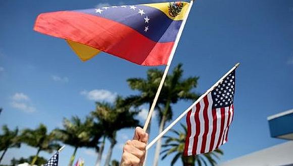 Hand holding small US and Venezuelan flags. File photo.