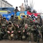 Featured image: Ukrainian neo-nazis pose with weapons and flags carrying nazi symbols as well as a NATO flag. File photo.