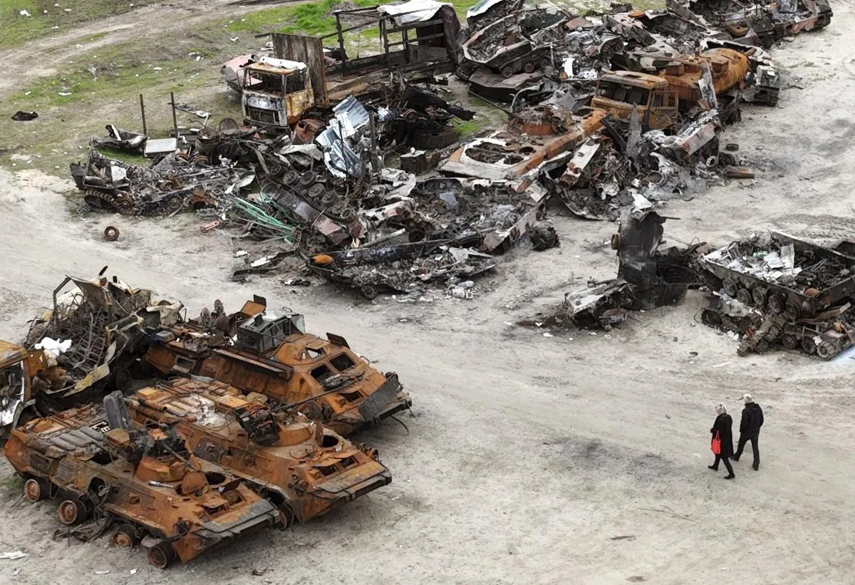 Two residents walking through destroyed tanks and trucks. Photo: The Hamilton Spectator.