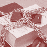 Featured image: Laptop computer with mouse, book and smartphone in chains. File photo.