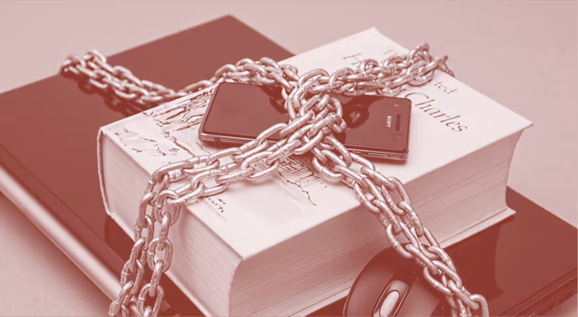 Featured image: Laptop computer with mouse, book and smartphone in chains. File photo.