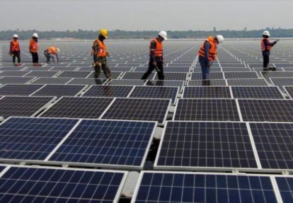 Workers inspect a solar panel installation. Photo: AP.