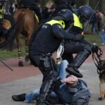 Dutch riot police kick a man during a demonstration to protest government policies including COVID-19 curfew, lockdown, and related restrictions in The Hague. Photo: Peter Dejong/AP.
