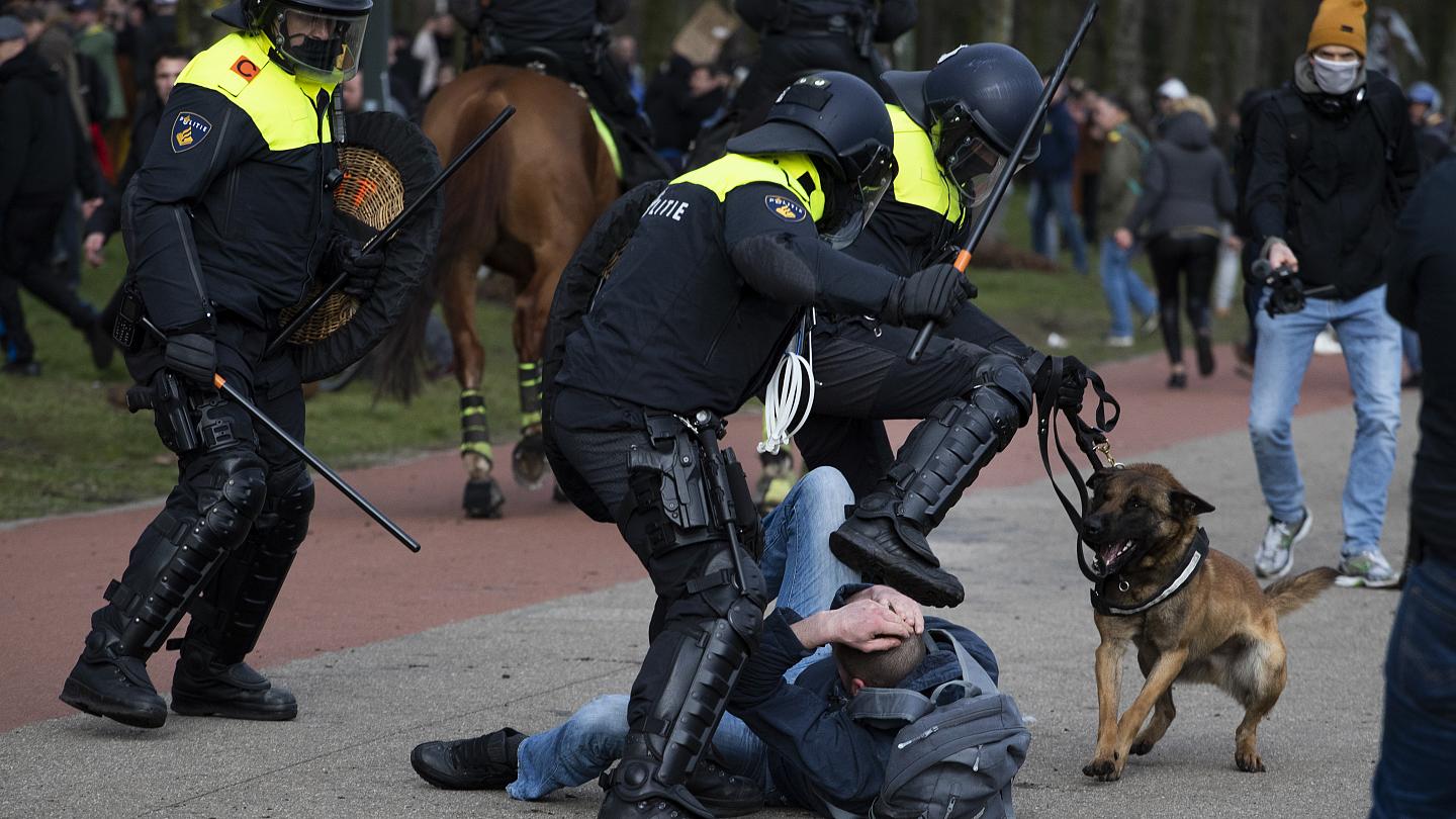 Dutch riot police kick a man during a demonstration to protest government policies including COVID-19 curfew, lockdown, and related restrictions in The Hague. Photo: Peter Dejong/AP.