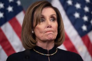 Nancy Pelosi bites her lips with US flags in the background. File photo: AFP.