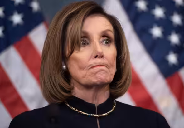 Nancy Pelosi bites her lips with US flags in the background. File photo: AFP.