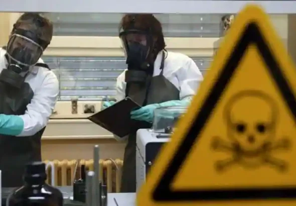 Two workers wearing bio-security gear and taking notes behind a warning sign. File photo.